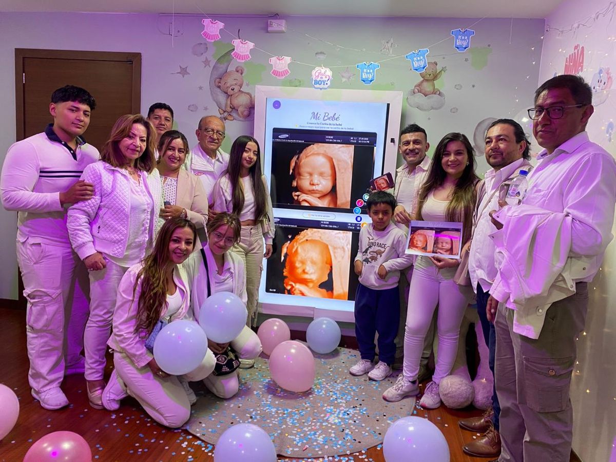 Una familia grande frente a la pantalla con la ecografía de su bebé
