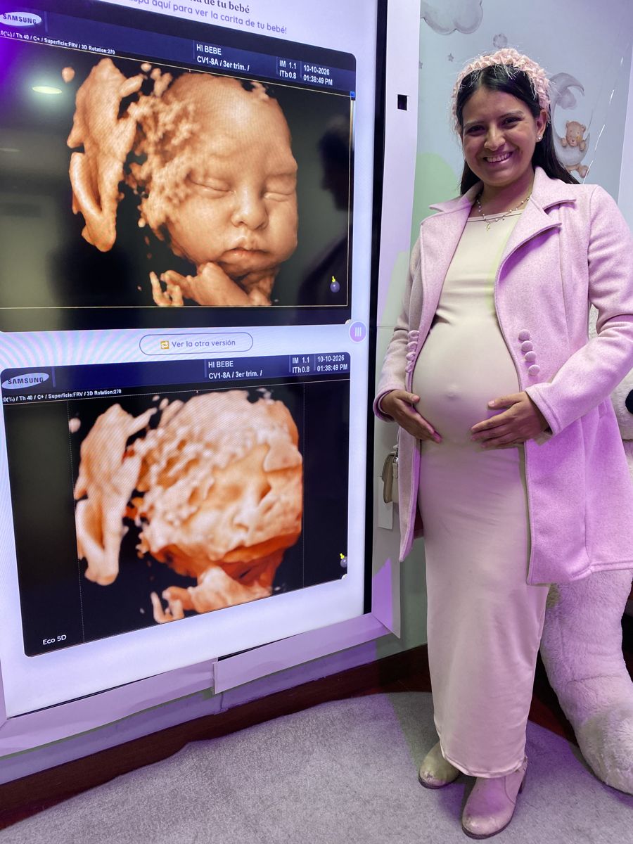 Una futura mamá sonríe junto a la pantalla con su bebé